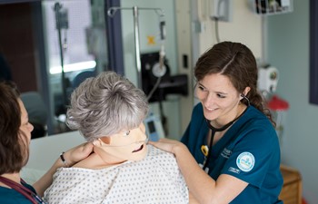 Student using stethoscope on practice dummy.