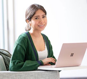 student in green sweater at laptop on campus