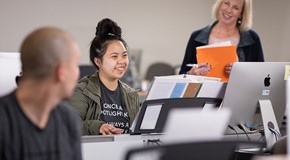 smiling student in music classroom at keyboard and computer
