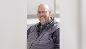 Person smiling, wearing glasses and a vest.