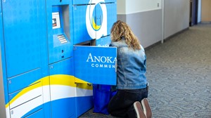 A person is crouched in front of a vibrant blue locker system labeled 'Anoka Community', seemingly interacting with it or retrieving items.